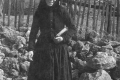 Rozália Potocká od Šándorov, fotené pred Mašírovcami (bývalá pošta). Fotka z roku približne 1920. Vydatá žena v čiernom odeve